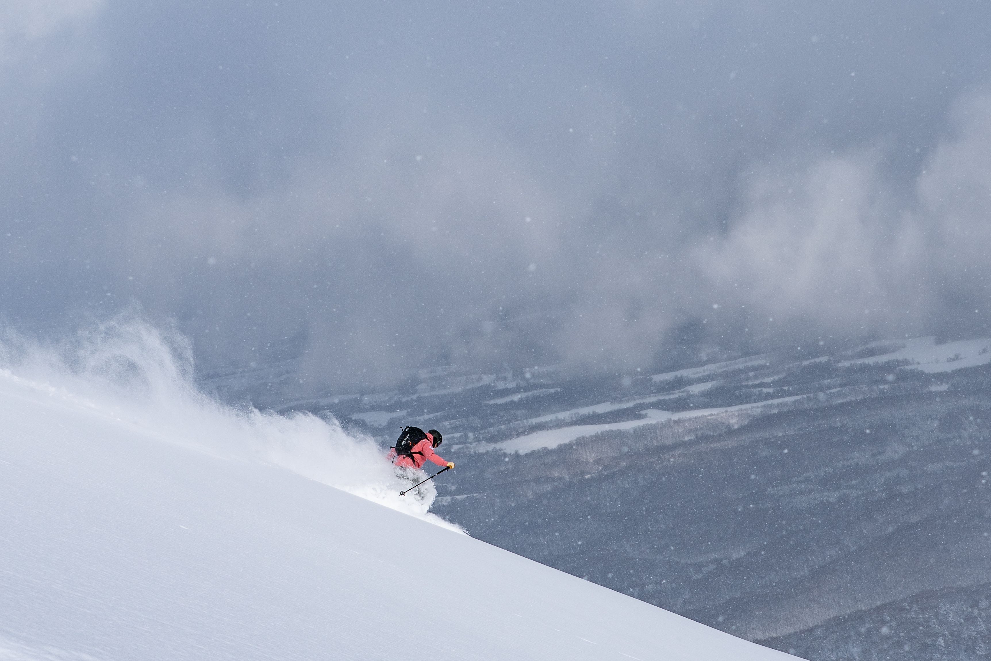 Skier skiing hard off the top of Niseko